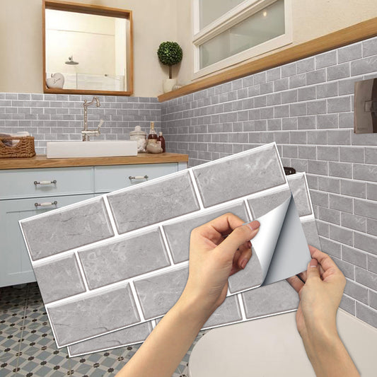 Person applying gray brick-patterned wall stickers to a bathroom wall.